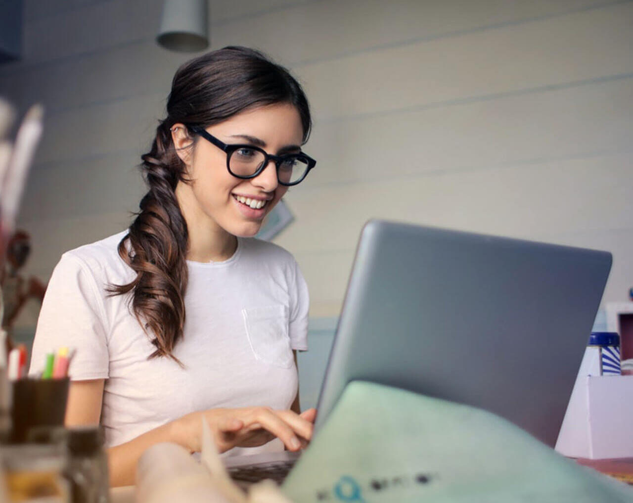 Woman search flight ticket Young woman in glasses smiling while working on a laptop to plan a trip.